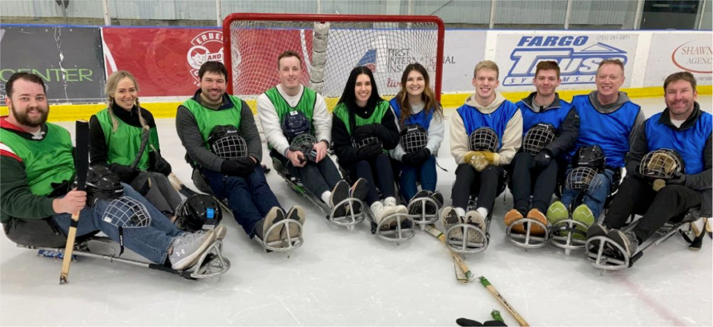 Group photo from AdShark Marketing at the Hope Inc. sled hockey tournament. From left to right: Eric Anderson, Whitney Jensen, Sean Maki, Jack Yakowicz, Sam Carver, Kayla Due, Evan Engler, Nick Due, Chris Jensen, Rick Berg.